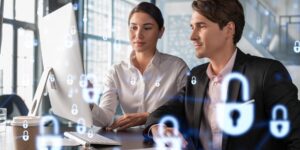 Businessman and businesswoman working together to protect clients confidential information and cyber security. IT hologram padlock icons over office background with panoramic windows.
